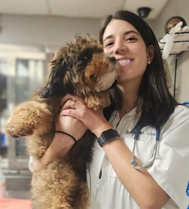 Dr. Hannah Allen smiling and holding a fluffy dog Dr. Hannah Allen smiling and holding a fluffy dog
